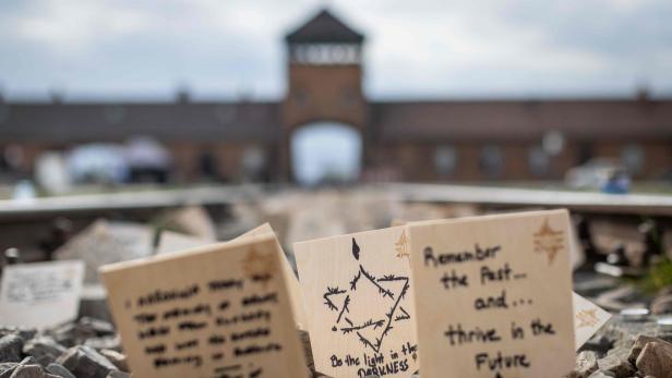 Auf Gleisen liegen Gedenktafeln mit Botschaften vor dem Tor von Auschwitz.