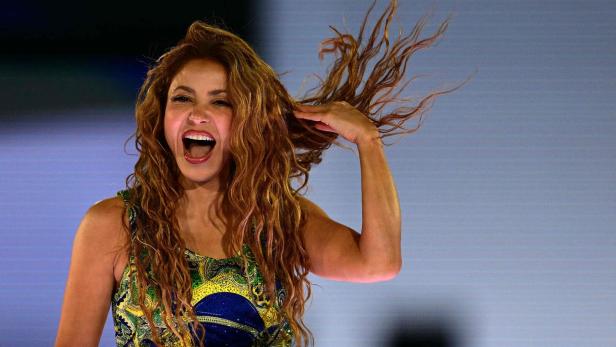 Shakira wirft lachend ihre lockigen Haare in die Luft.
