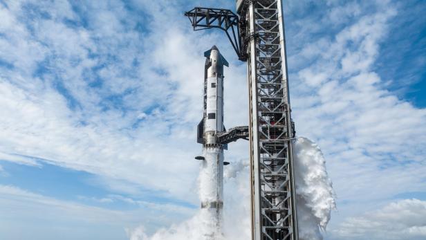 Die Starship-Rakete steht rauchend auf der Startrampe in Texas unter blauem Himmel.