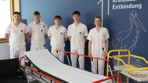 Fünf Zivildiener hinter einem Krankenhausbett