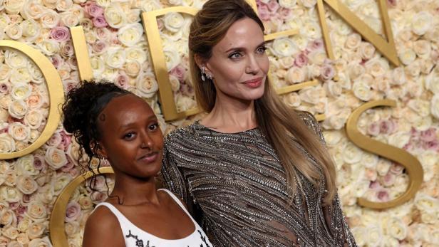 Angelina Jolie posiert mit Tochter Zahara vor einem Rosenhintergrund.