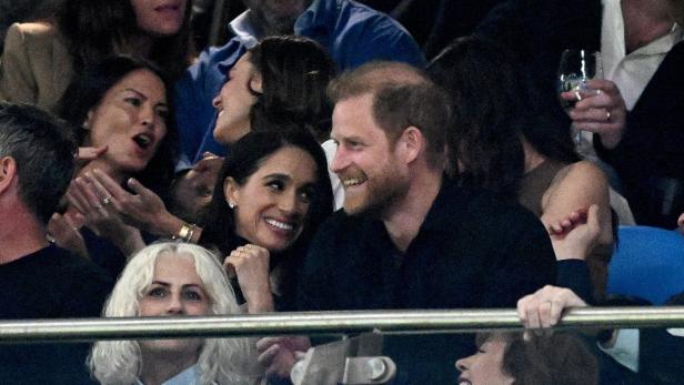Prinz Harry und Meghan, die Herzogin von Sussex, lächeln inmitten einer Menschenmenge.