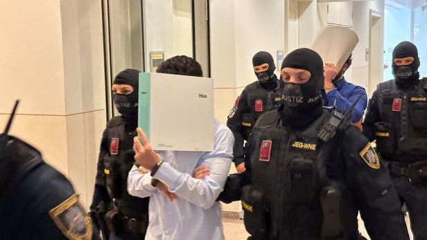 Justizwachebeamte mit Sturmhauben führen zwei Angeklagte vor