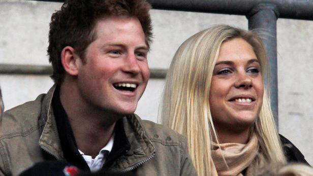 Prinz Harry und Chelsy Davy lächeln auf einer Tribüne.