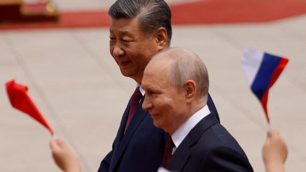 Xi Jinping und Wladimir Putin gehen an winkenden Flaggen vorbei.