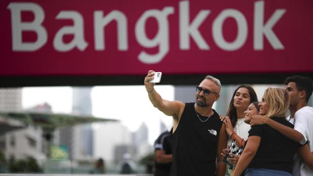 Eine Gruppe von Leuten macht ein Selfie vor einem Schild mit der Aufschrift "Bangkok".