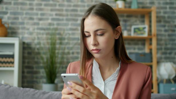 eine Frau schaut bestürzt auf ihr Handy