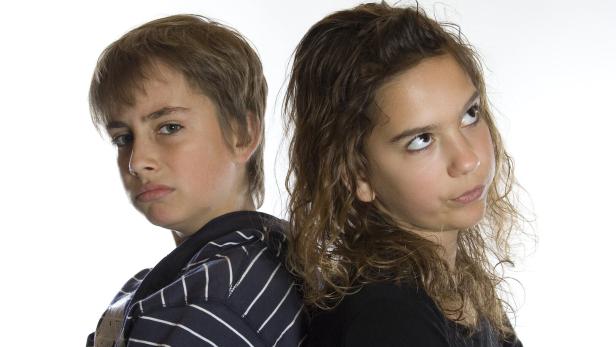 Zwei Kinder stehen Rücken an Rücken und schauen mit genervtem Gesichtsausdruck in entgegengesetzte Richtungen.
