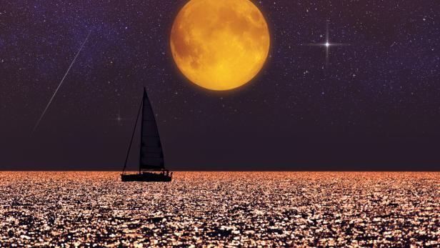 Ein Segelboot fährt über ein funkelndes Meer bei Nacht, darüber ein großer Vollmond und ein sternklarer Himmel.