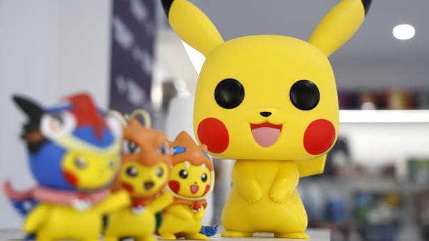 Mehrere bunte Pikachu-Figuren stehen nebeneinander auf einer weißen Oberfläche, eine davon ist besonders groß.