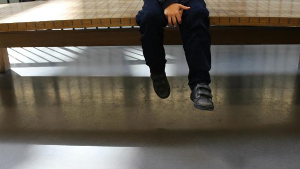 Kind sitzt auf Bank und wartet 