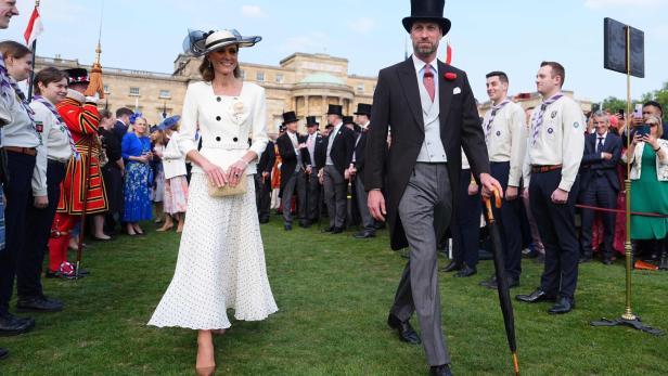 Kate und William gehen über einen Rasen, umgeben von Zuschauern.