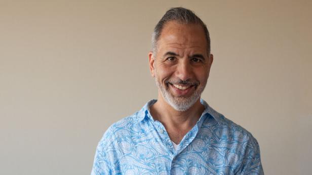 Yotam Ottolenghi steht an einem Schneidbrett und filetiert Zitronen