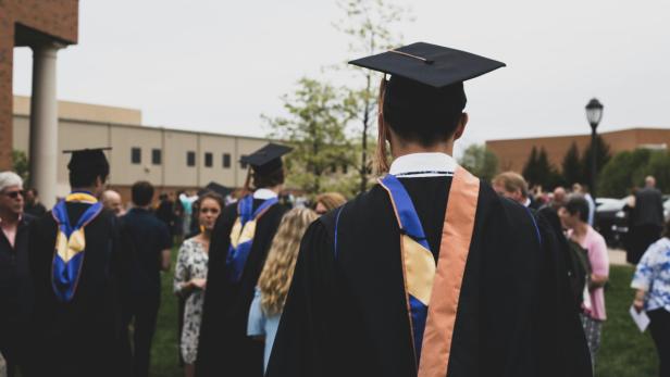 Mehrere Schüler vor einer High School beim Abschluss