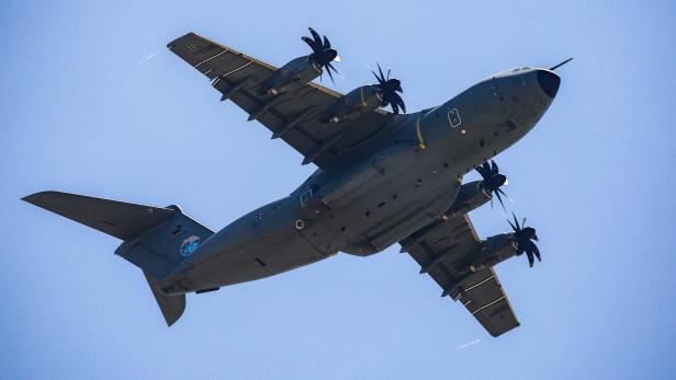 Ein graues Militärflugzeug mit Propellern ist vor blauem Himmel zu sehen.