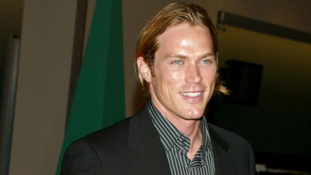 Jason Lewis mit halblangen Haaren, gestreiftem Hemd und Anzug.