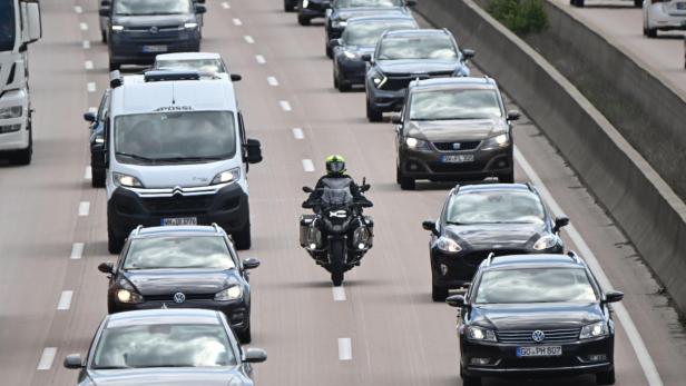 Motorradfahrer zwischen dichtem Auto- und Lieferwagenverkehr auf mehrspuriger Autobahn.