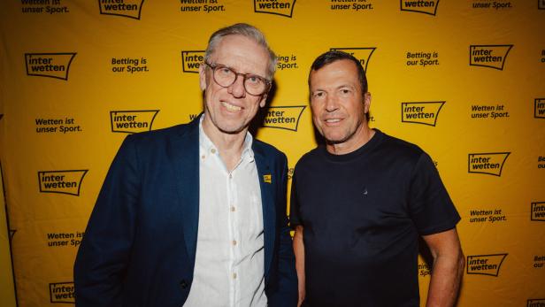 Peter Stöger und Lothar Matthäus posieren vor einer Sponsor-Wand.