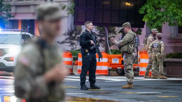 Ein Polizist mit Gewehr spricht mit einem Soldaten der Nationalgarde auf der Straße.