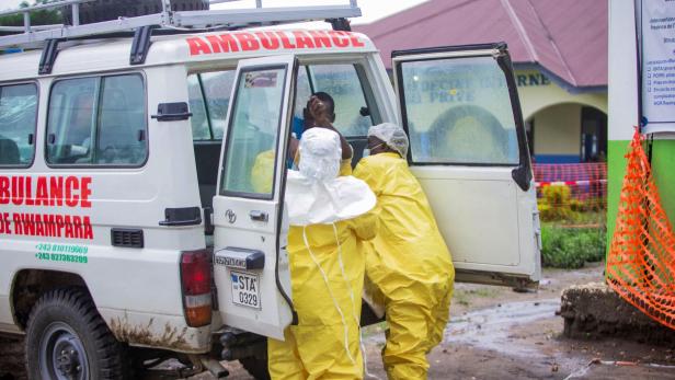 Sanitäter in Schutzkleidung stehen an einem Krankenwagen in Ruanda.