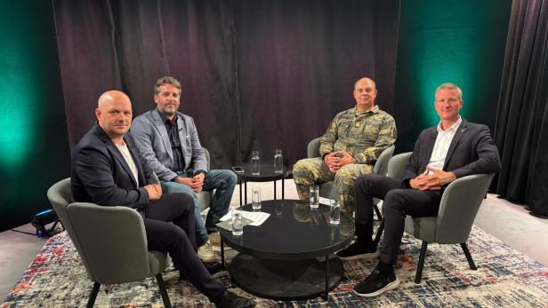 Vier Männer sitzen nebeneinander