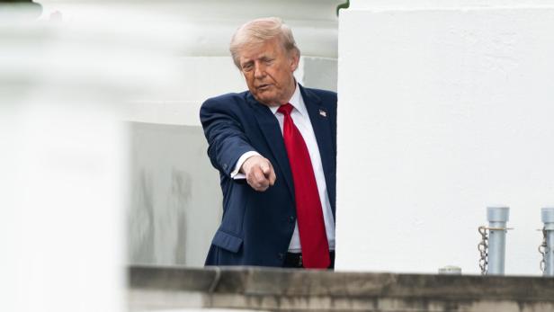Donald Trump im Anzug mit roter Krawatte deutet mit dem Finger.