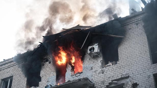 Ein Backsteingebäude steht in Flammen, dichter Rauch steigt auf.