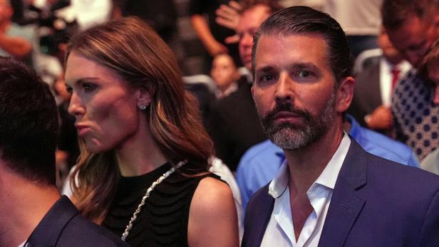 Donald Trump Jr. mit Bart und Bettina Anderson mit Halskette sitzen im Publikum.