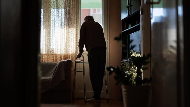 Elderly man with walker looking out window, contemplating life in quiet solitude