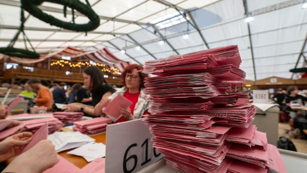 Viele Wahlhelfer sortieren in einem Zelt rote Wahlbriefe.