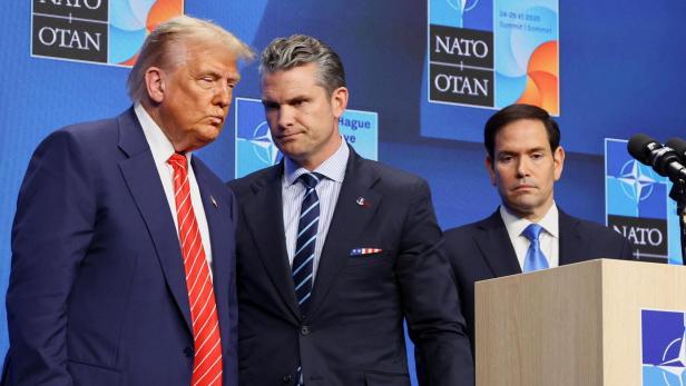 Donald Trump und weitere Personen stehen vor einem NATO-Hintergrund.