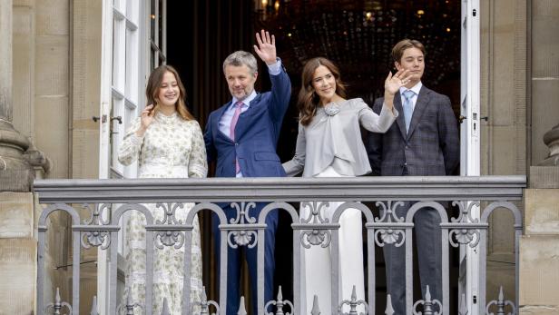 Die dänische Königsfamilie winkt von einem Balkon mit verzierten Geländern.