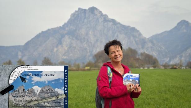 Frau mit ALPINE Parkuhr von KUNSTVOLLER vor Berglandschaft auf einer Wiese.
