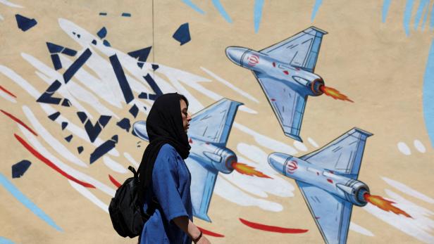 An Iranian woman walks next to an anti-Israeli mural on a street in Tehran