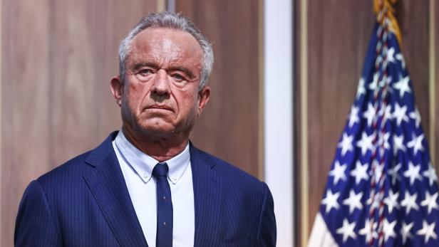 Robert F. Kennedy Jr. im Anzug steht vor einer amerikanischen Flagge.