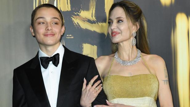 Angelina Jolie, mit Schmuck und goldenem Kleid, posiert mit Sohn Knox im Smoking.