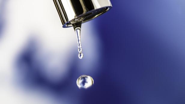 Ein Tropfen Wasser fällt von einem Wasserhahn.