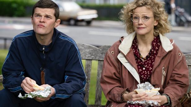 Maxine Peake und Robert Aramayo sitzen als Dottie und John auf einer Parkbank.