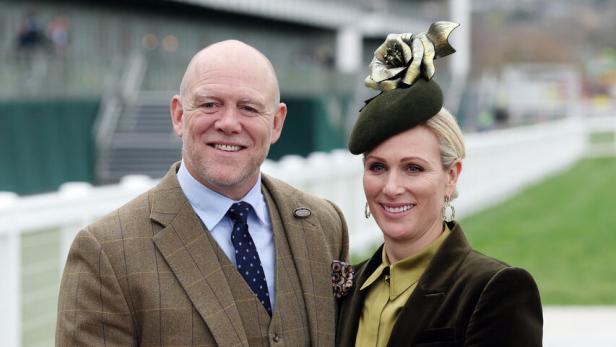 Mike Tindall im Tweedanzug und Zara Tindall mit Hut und Clutch lächeln in die Kamera.