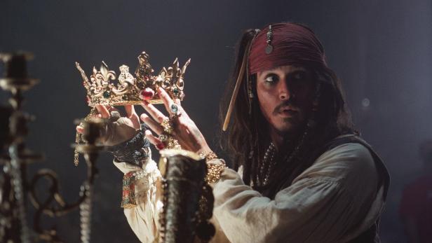 Johnny Depp als Captain Jack Sparrow hält eine Krone in den Händen.