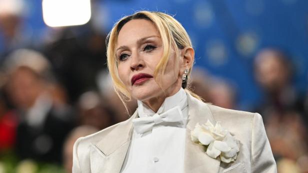 Madonna trägt einen hellen Anzug mit Fliege und einer weißen Blume am Revers.