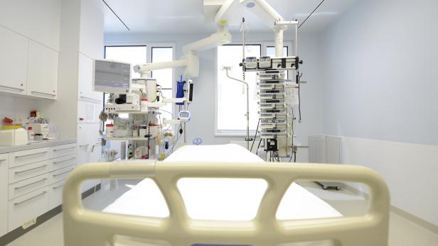 Krankenhauszimmer mit leerem Bett, medizinischen Geräten, Monitoren und Infusionspumpen in heller Umgebung.