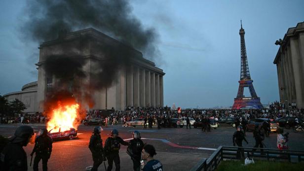Ein Auto brennt in Paris - im Hintergrund der Eiffelturm.