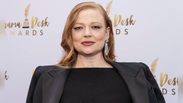 Sarah Snook mit Blazer und Ohrringen vor dem Hintergrund der Drama Desk Awards.