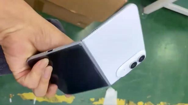 Eine Hand hält ein klappbares Smartphone mit weißer Rückseite