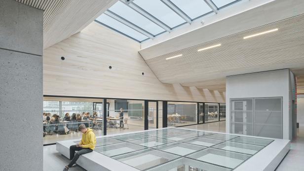 Innenaufnahme der TU Bau und Design in Innsbruck. Viel Holz und Glas zeichnen das Gebäude aus. 