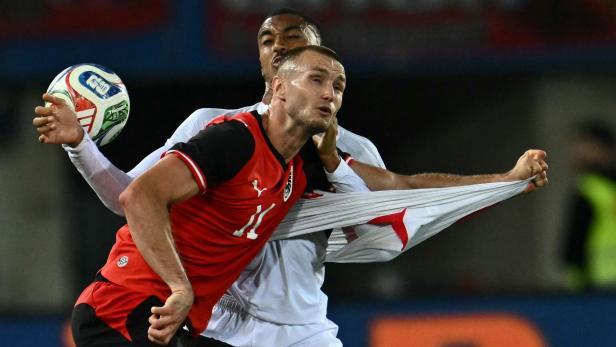 Zwei Fußballspieler kämpfen um den Ball, einer zieht am Trikot des anderen.
