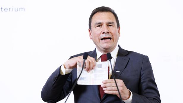 Ein Mann im Anzug spricht an einem Rednerpult und hält ein aufgeschlagenes Dokument in den Händen.