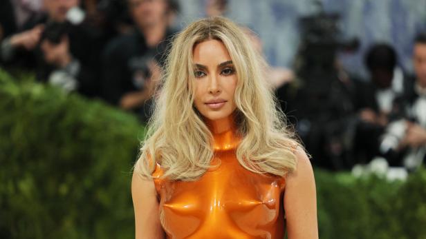 Kim Kardashian mit blonden Haaren und orangefarbenem Oberteil.