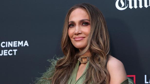 Jennifer Lopez mit langen Haaren lächelt und trägt ein grünes Kleid